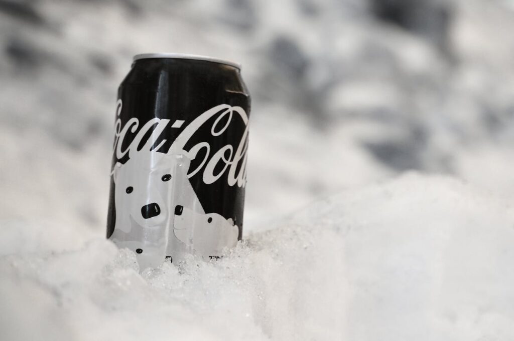 A close-up of a Coca-Cola can covered in frost and surrounded by snow, evoking a wintery and refreshing feel.